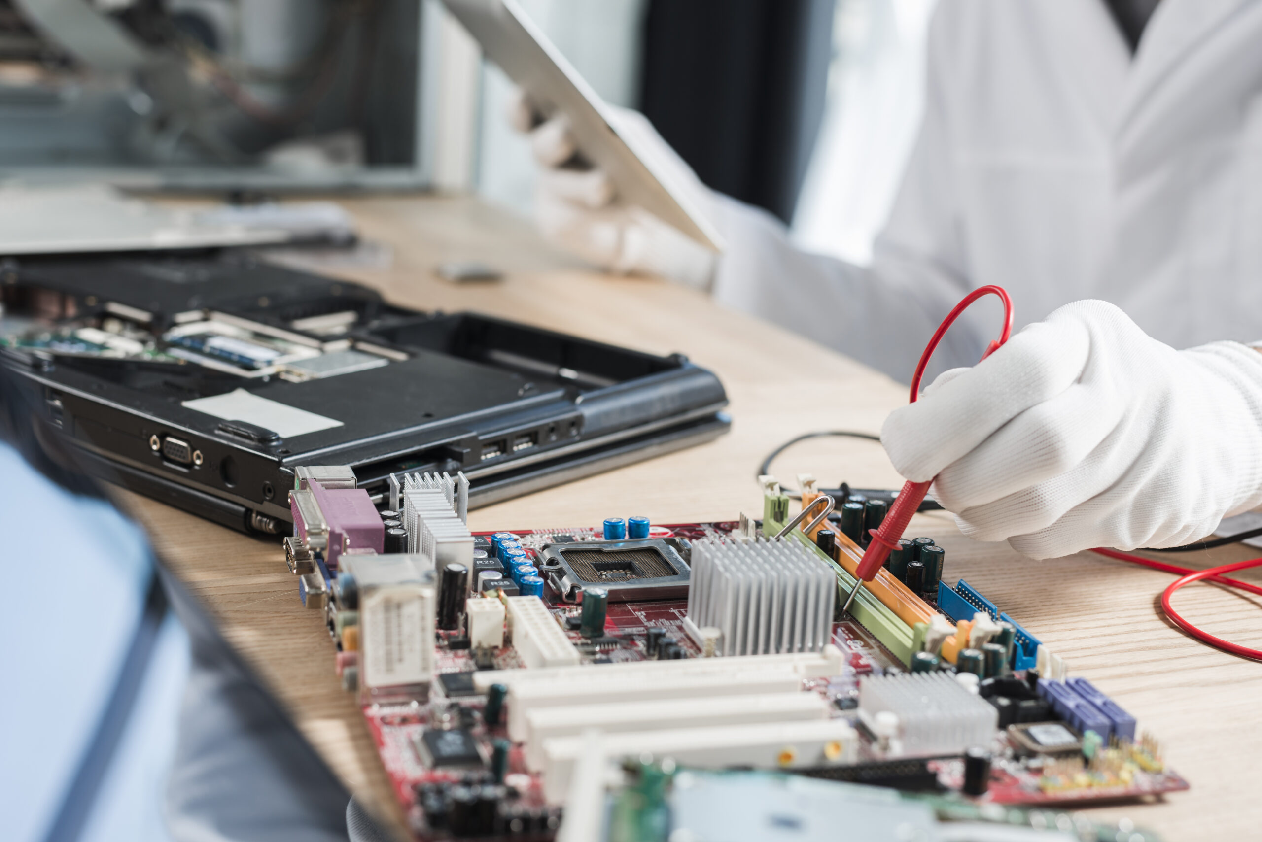 male technician examining mother board with digital multimeter scaled